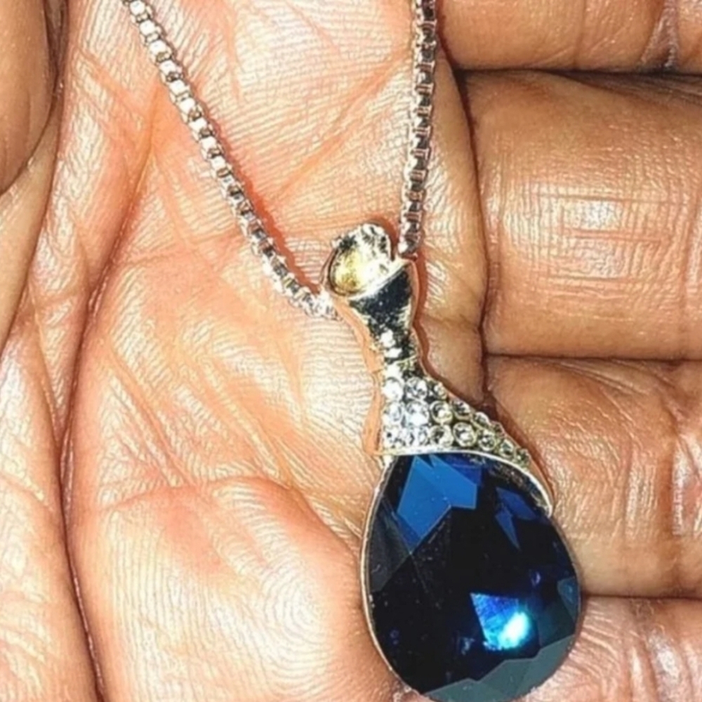 This stunning Golden necklace features a deep blue teardrop Gemstone